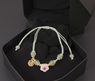 Pulsera feng shui de cordón verde con cuentas verdes, flor blanca y detalles dorados para amor y fortuna