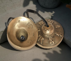 Crótalos tibetanos de 6 cm sobre superficie decorativa, ideales para espacios de meditación o limpiezas energéticas