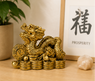 Figura dorada de Dragón Chino sobre monedas, símbolo Feng Shui de prosperidad y buena fortuna
