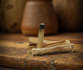 Vara de Palo Santo encendida, liberando humo en ritual de purificación
